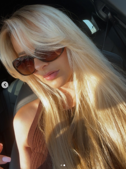 Creamy blonde hair with curtain bangs gives a soft, romantic, and trendy appearance.