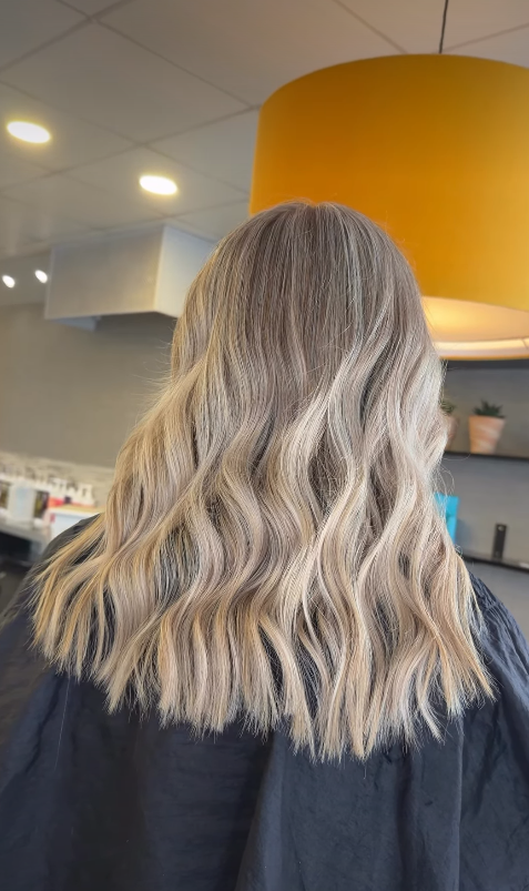 Creamy blonde beach waves on a textured lob create a soft, fresh, and effortless hairstyle.
